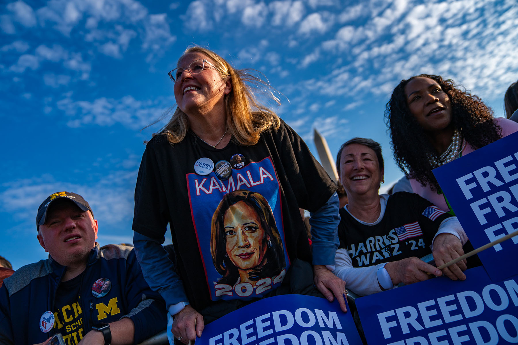 Crowd members cheer before a speech by Vice President Harris in Washington, D.C. Most hold signs that read "Freedom."