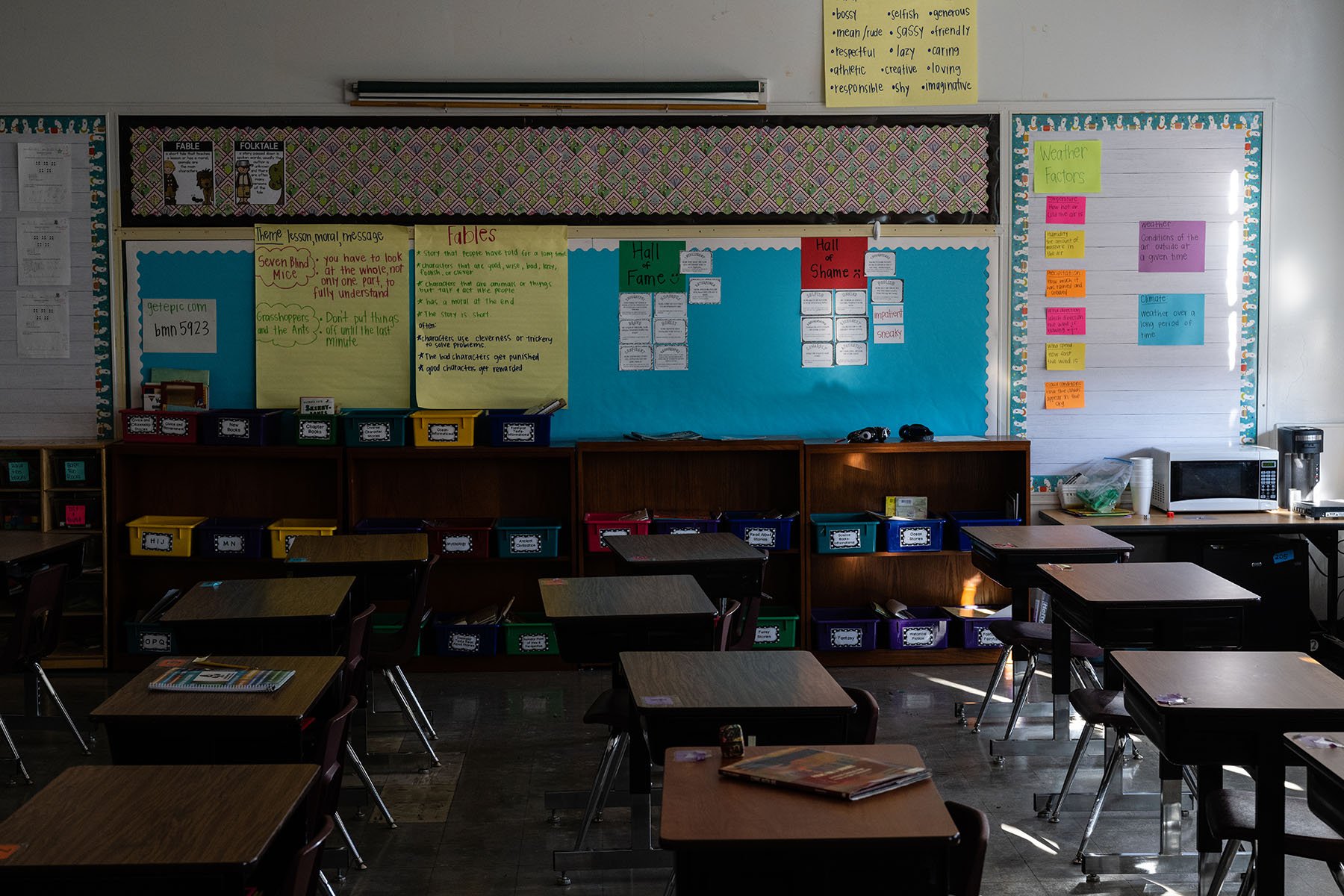 empty desks and cubbies are seen in a classroom.