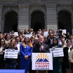 Gov. Jared Polis and legislators celebrate the passage of SCR24-003l during a press conference on the steps of the Colorado State Capitol.