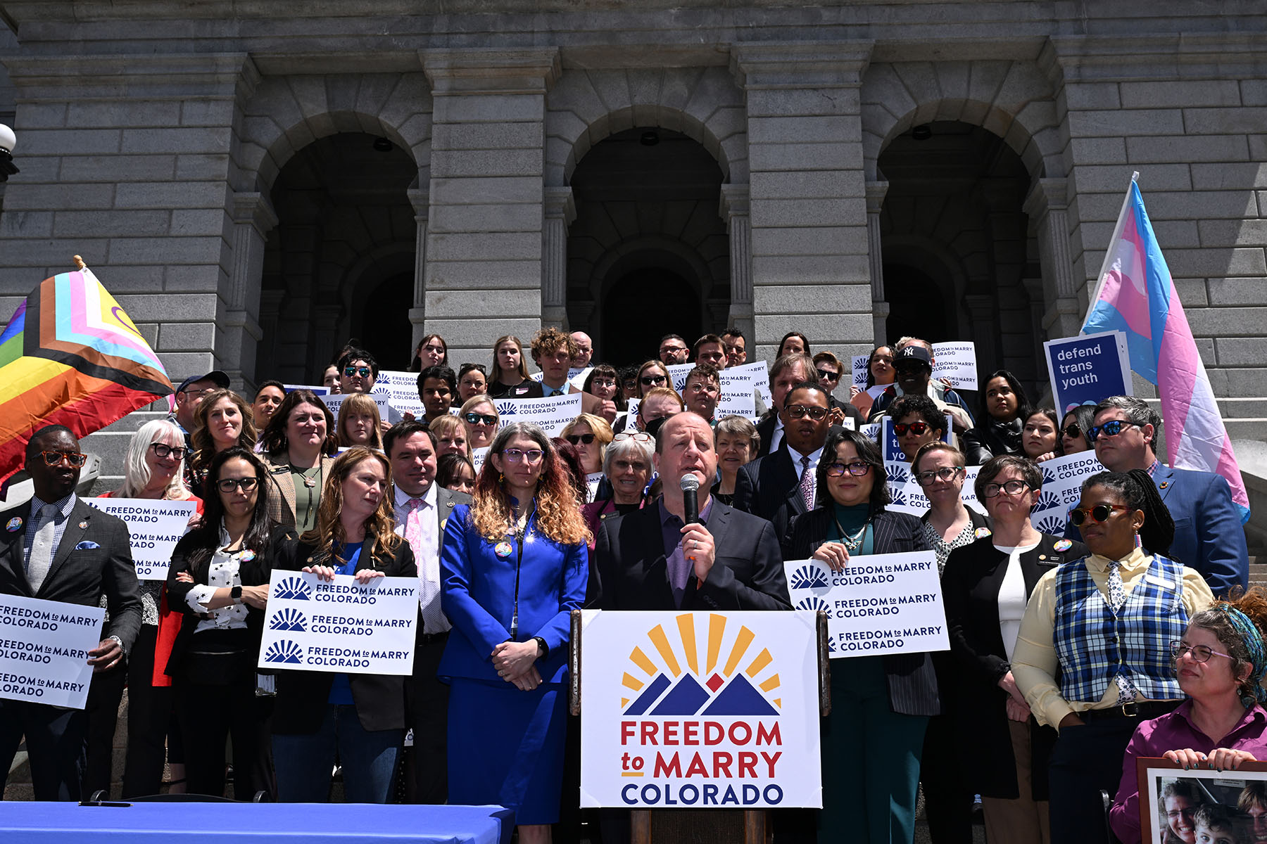 Gov. Jared Polis and legislators celebrate the passage of SCR24-003l during a press conference on the steps of the Colorado State Capitol.