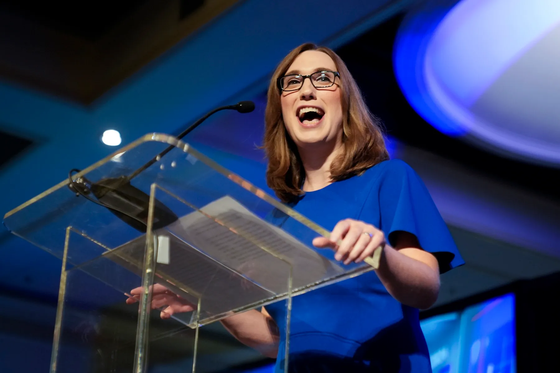 A woman smiles while standing at a podium.