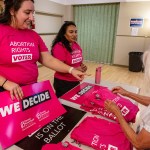 Rally-goers handle signs and shirts displaying abortion rights slogans before a rally.