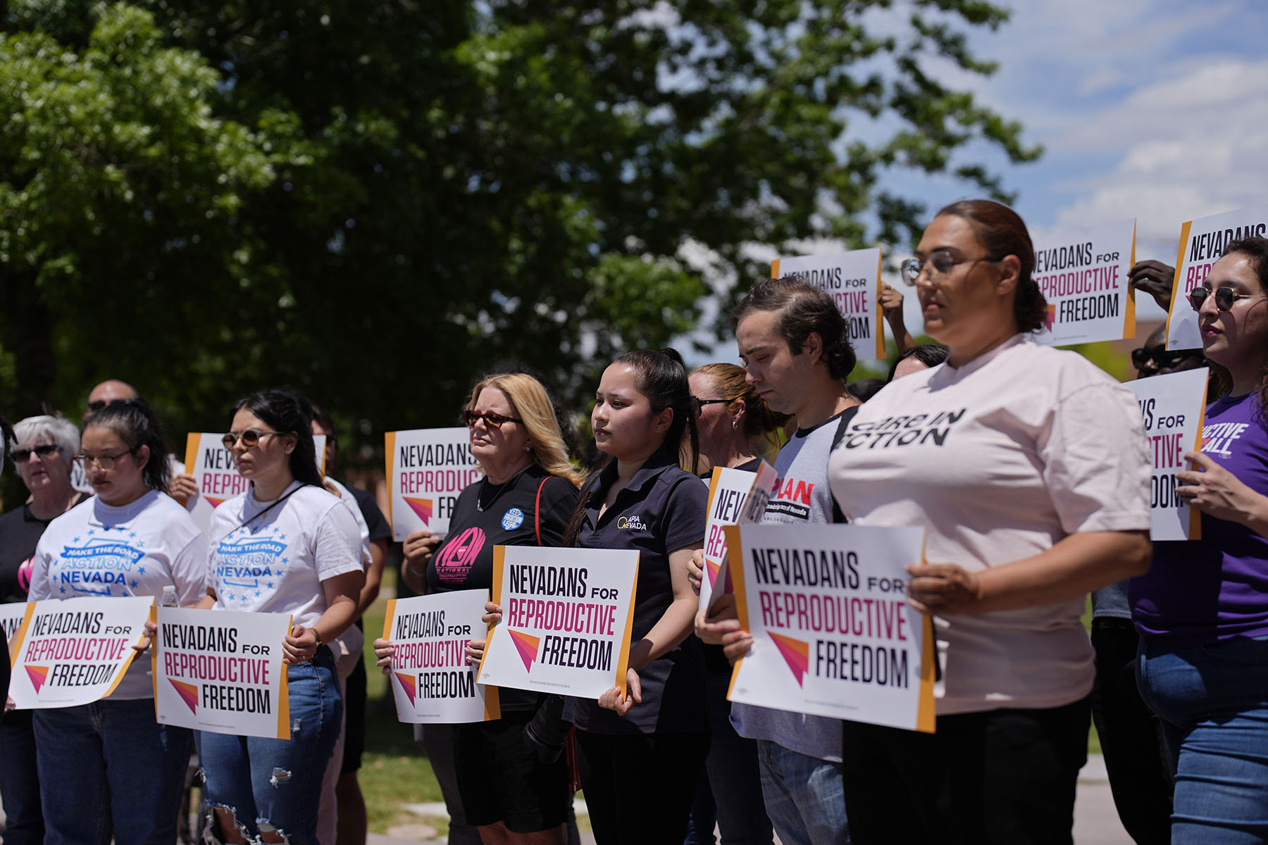 People hold signs during a news conference by Nevadans for Reproductive Freedom in Las Vegas.