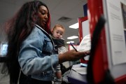 First-time voter Kayria Hildebran holds baby Kayden Hildebran as she fills out her ballot during in-person early voting.