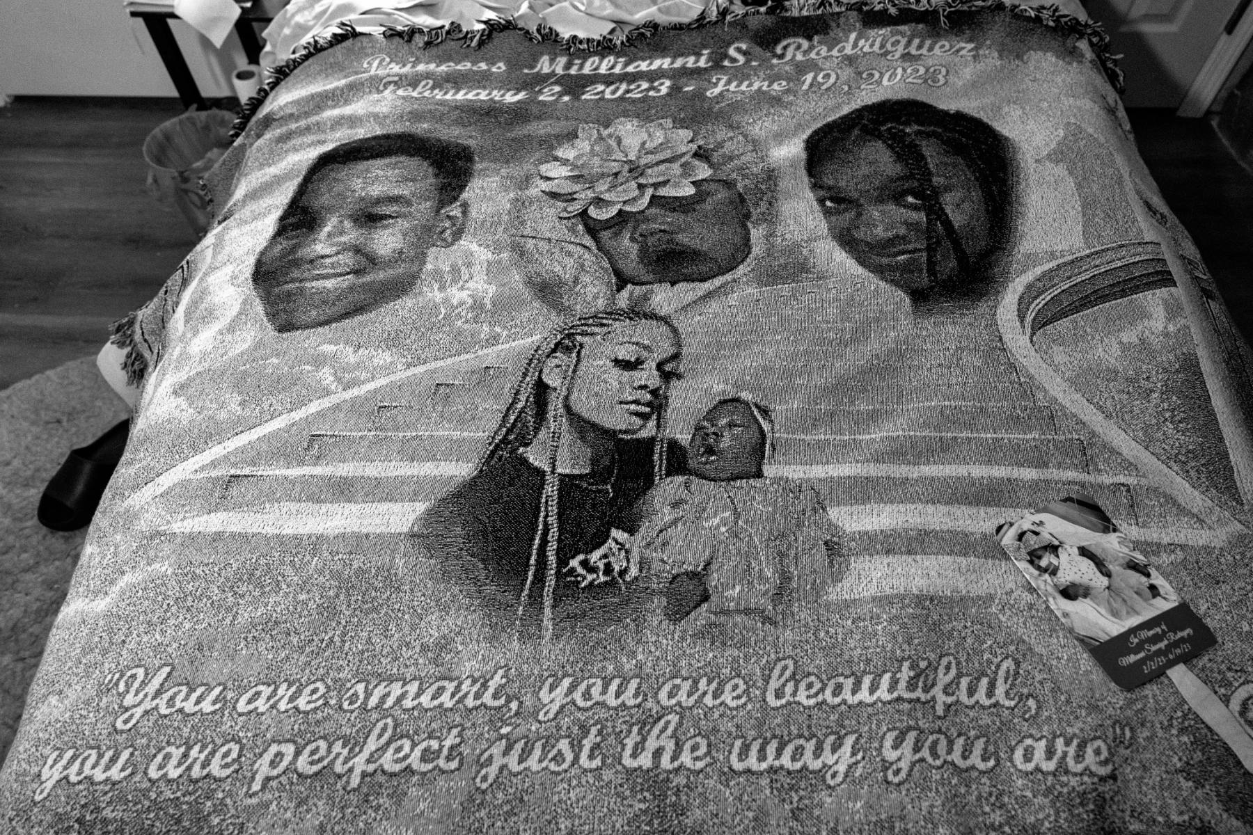 A blanket on a bed with the faces of children and a baby.