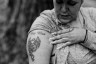 A woman shows a tattoo on her arm of a basketball with wings.