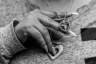 A closeup photo of a woman's hand lifting a necklace charm with a photo in a heart.