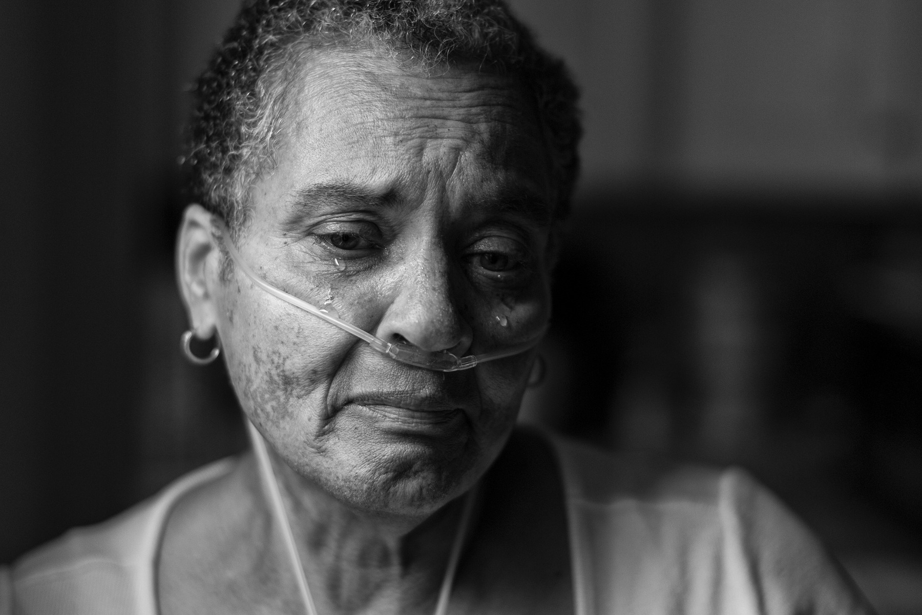 A woman with tubes in her nose sheds tears.