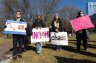 Young people stand together and hold signs the Boston Common.