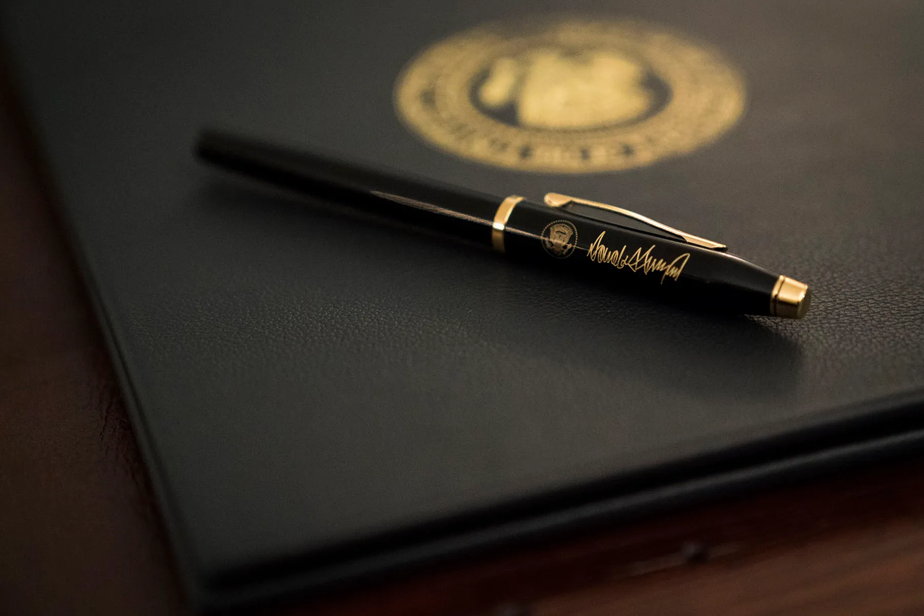 A pen and binder rest on a desk before President Trump signs an executive order.