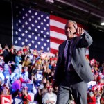 Robert F. Kennedy Jr. on stage with an American flag behind him.