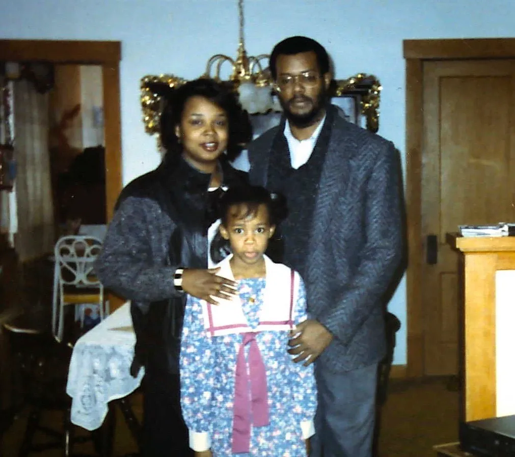 A family of three poses together for a photo.