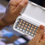 A woman holds a one-month’s prescription of birth control pills.