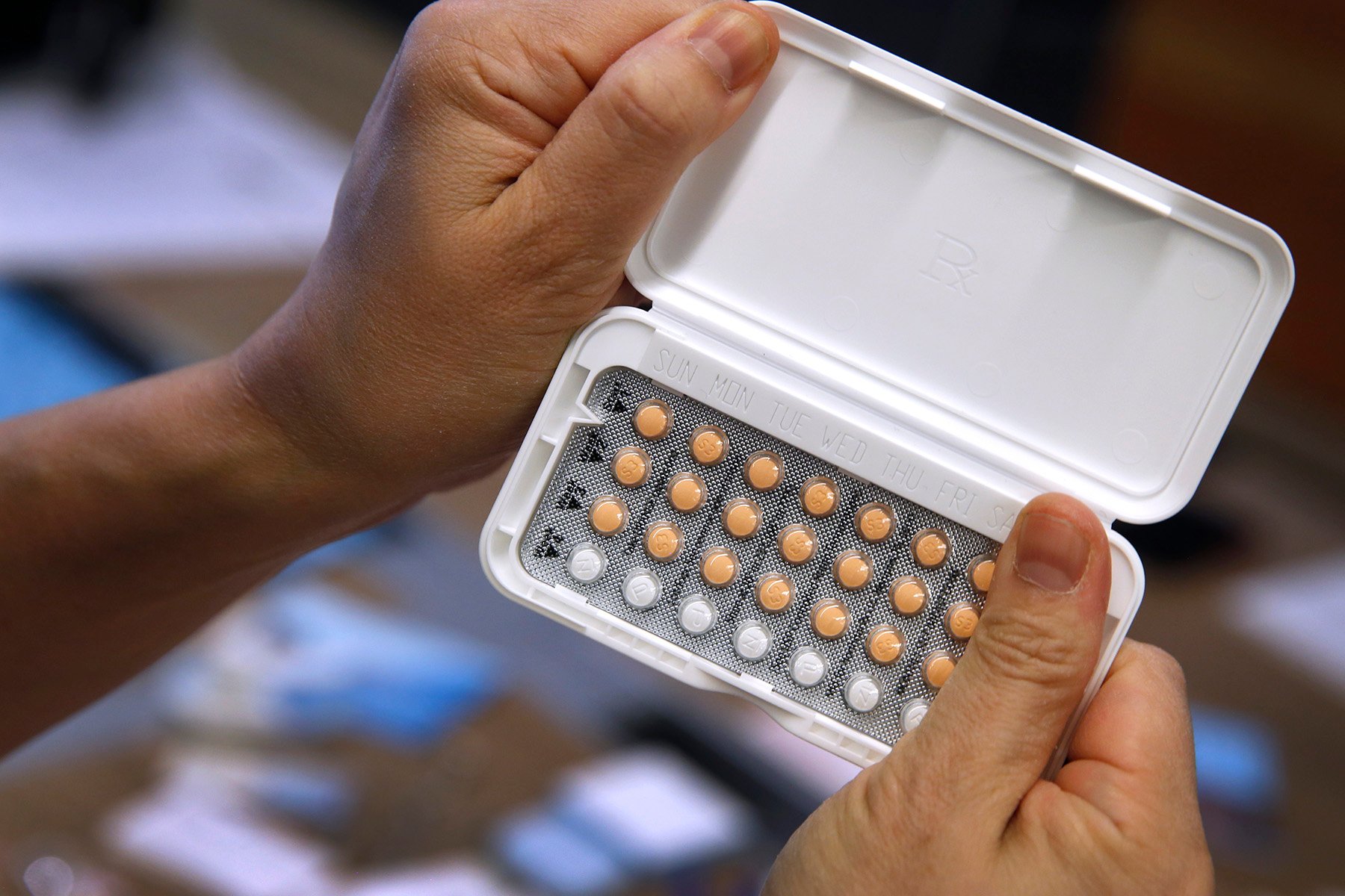 A woman holds a one-month’s prescription of birth control pills.