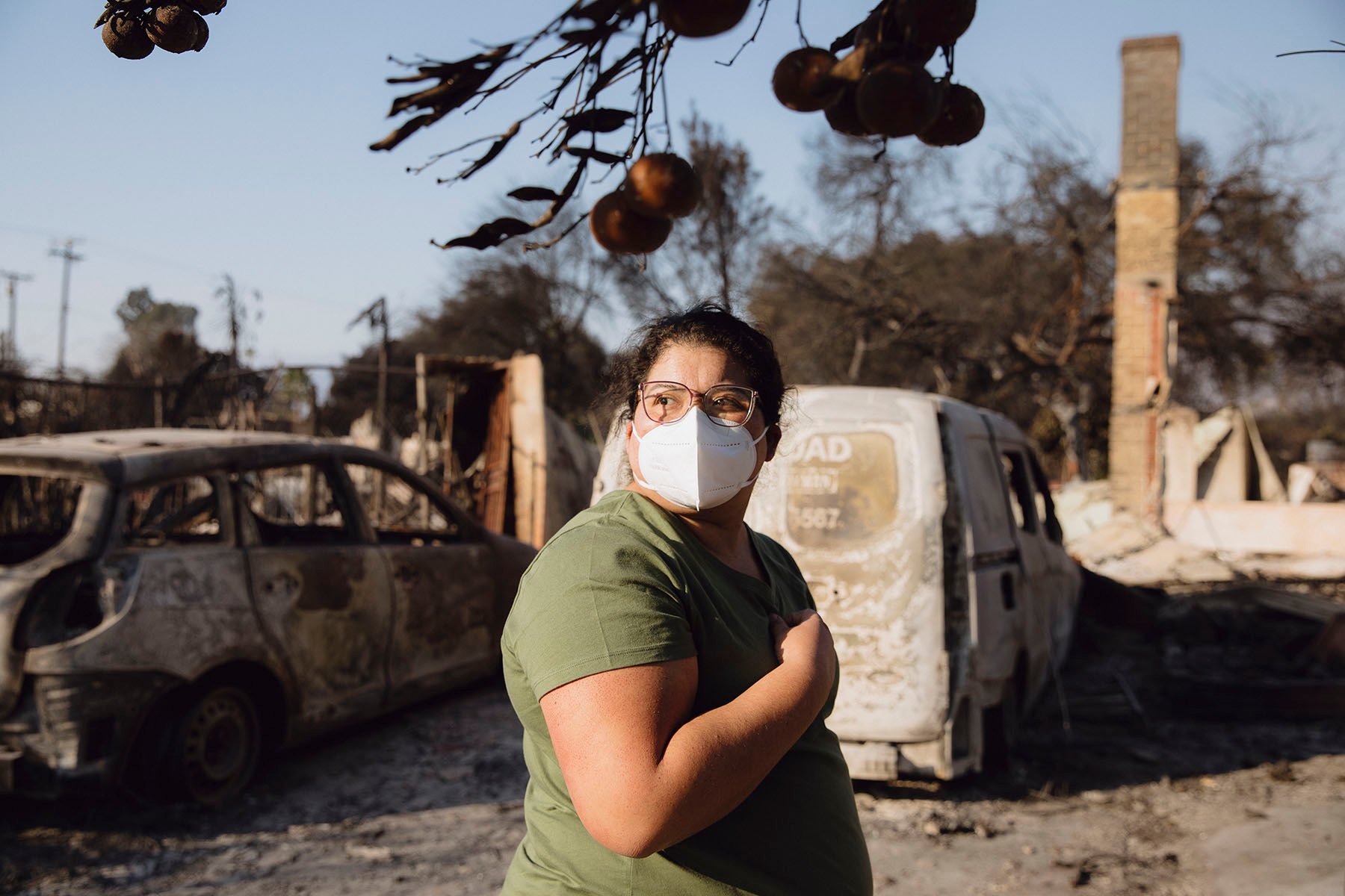 Sanchez wears a mask as she poses for a portrait in the rubble of her family home.