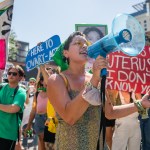 Abortion rights activists and supporters hold signs and speak into a megaphone.