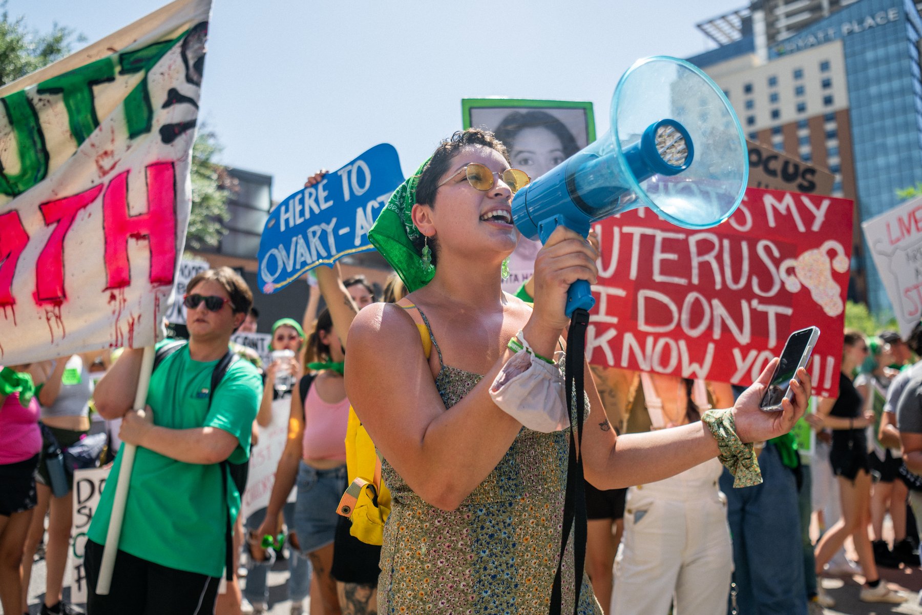 Abortion rights activists and supporters hold signs and speak into a megaphone.