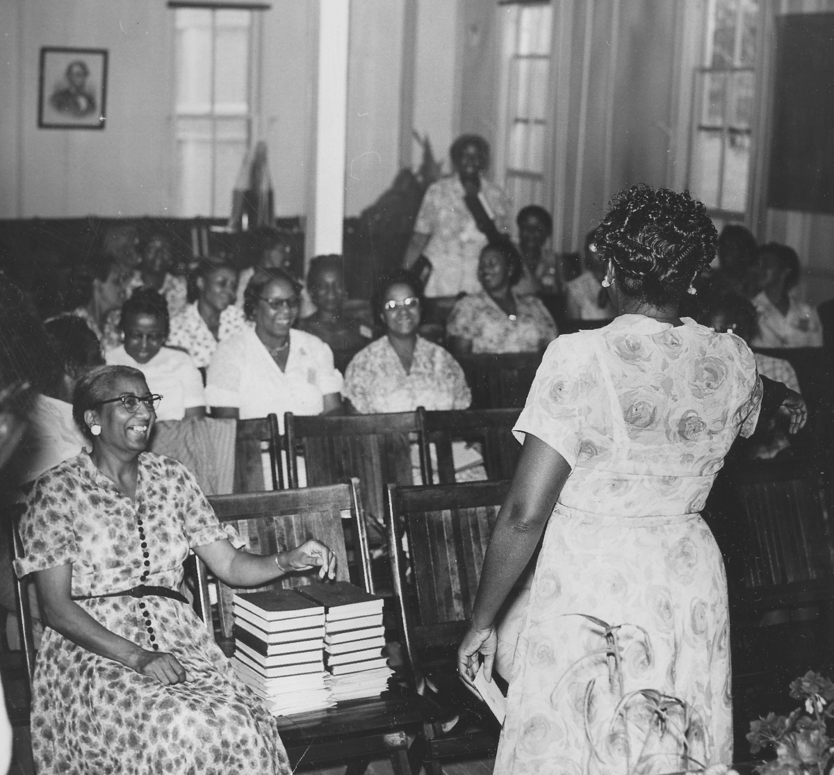 A black and white image of a group of teachers smiling in a classroom.