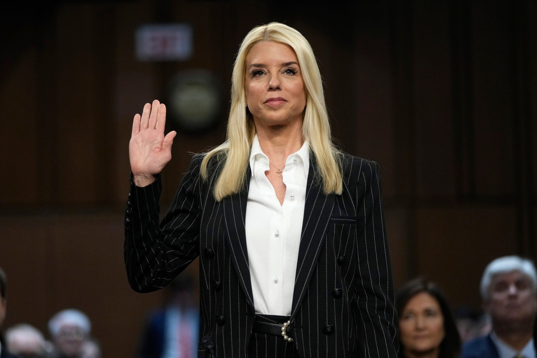 A standing woman raises her hand to be sworn in.