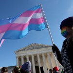 A person holds a pink and blue transgender rights flag outside of the U.S. Supreme Court building.