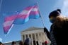 A person holds a pink and blue transgender rights flag outside of the U.S. Supreme Court building.