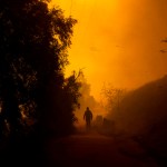 A firefighter walks on a path engulfed in smoke and embers as high winds push the Mountain Fire in Camarillo Heights, Camarillo, California.