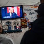 People watch the inauguration of President Trump at the Juventud 2000 shelter in Tijuana, Mexico, on January 20, 2024.