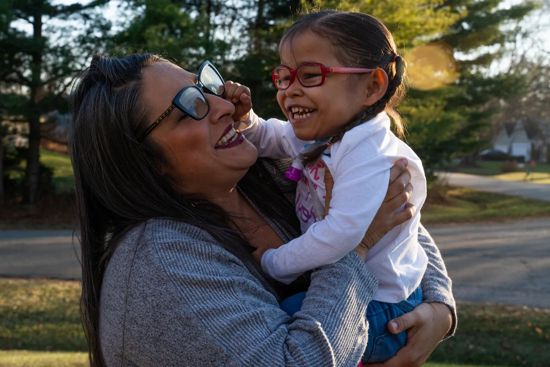 A mother holds her laughing daughter in her arms.