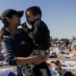 A mom holds her son as they look for clothes at a donation center in Santa Anita Park, Arcadia, California after being displaced by the Eaton Fire.