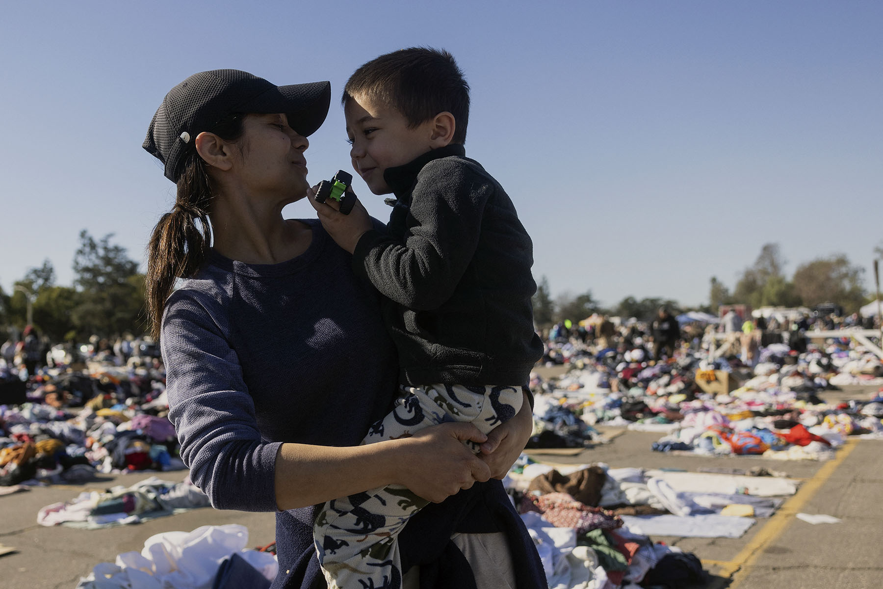 A mom holds her son as they look for clothes at a donation center in Santa Anita Park, Arcadia, California after being displaced by the Eaton Fire.