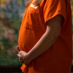 A pregnant inmate is seen holding her belly.