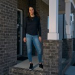 A woman stands on a front porch.