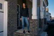 A woman stands on a front porch.