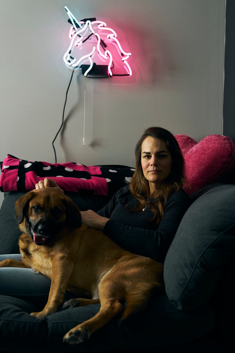 A woman sits on a couch with her dog.