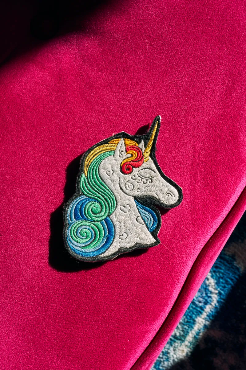 A unicorn patch lays on a bright pink surface.