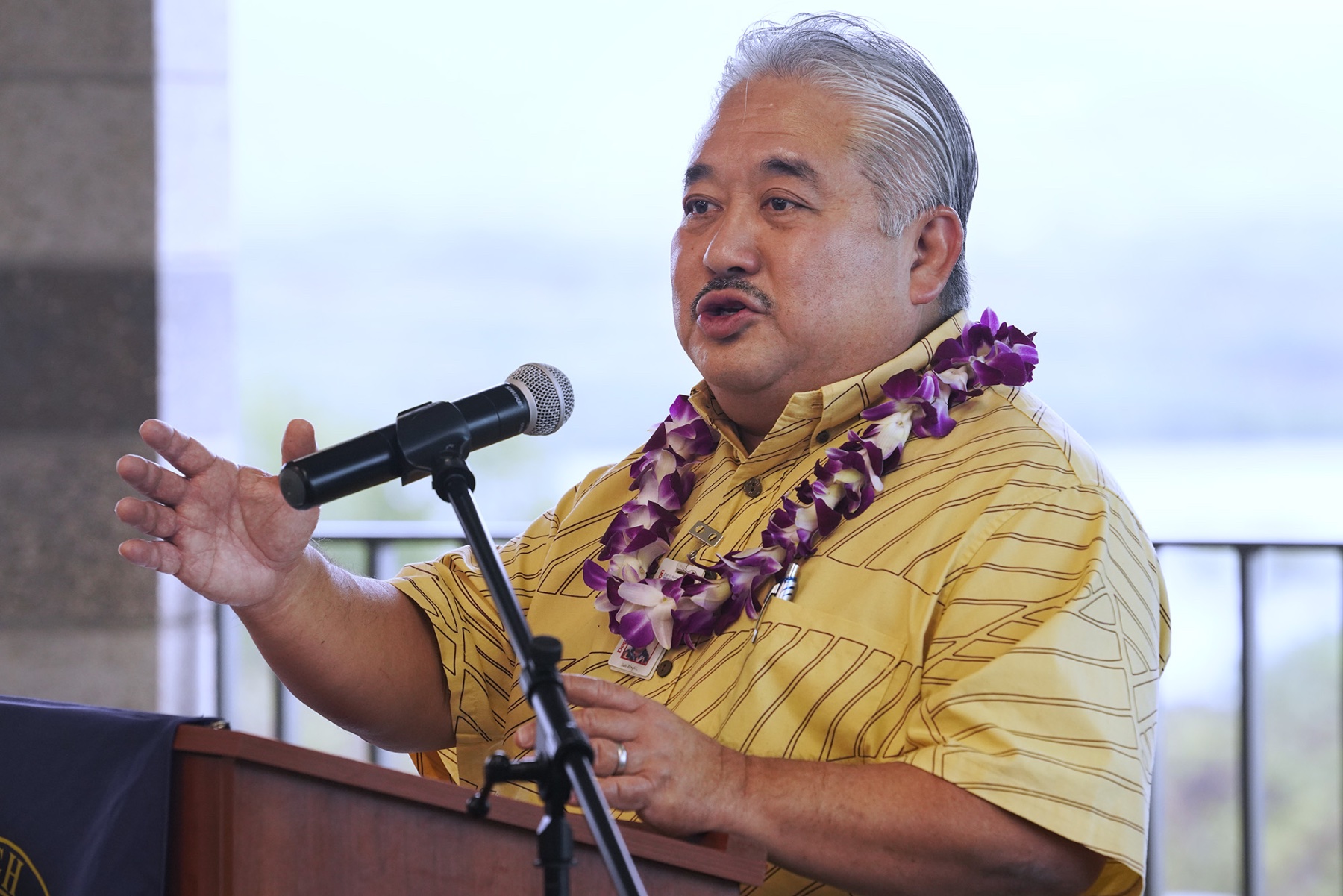 Department of Education Superintendent Keith Hayashi stands at a podium speaking into a mic.