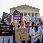 A group of doctors join abortion rights supporters at a rally outside the Supreme Court.