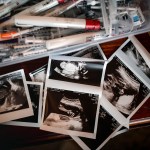 A container full of IVF needles, injections, syringes, old pill bottles and sonograms.