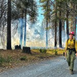 Kaleena Lynde stands in a smokey forest in her firefighter uniform.