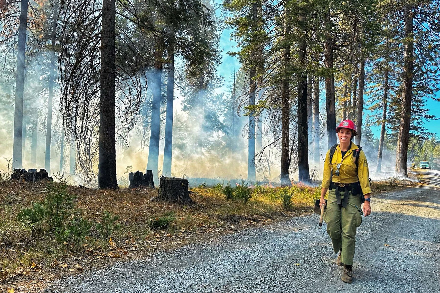 Kaleena Lynde stands in a smokey forest in her firefighter uniform.