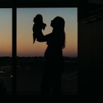 A silhouette of a person holding a child near a window.