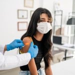 A doctor puts a bandage on a teen's arm.