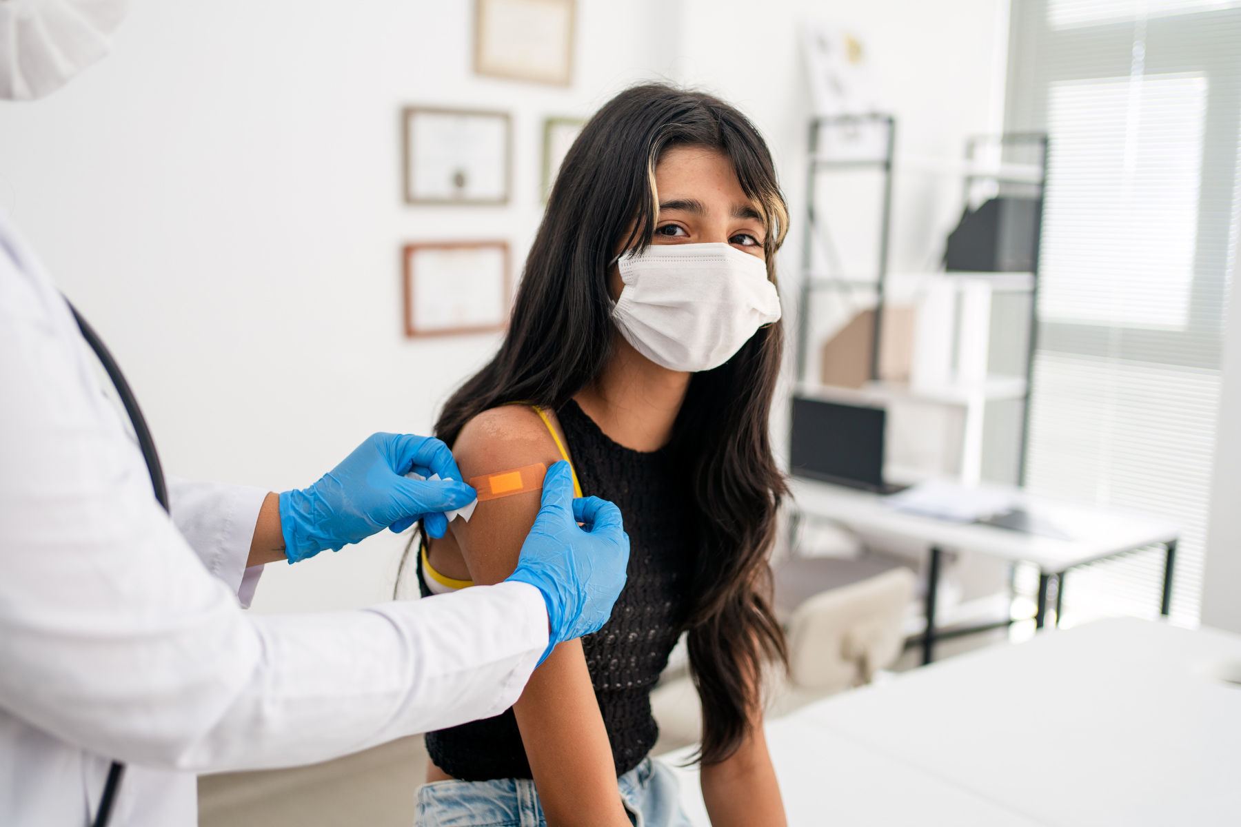 A doctor puts a bandage on a teen's arm.