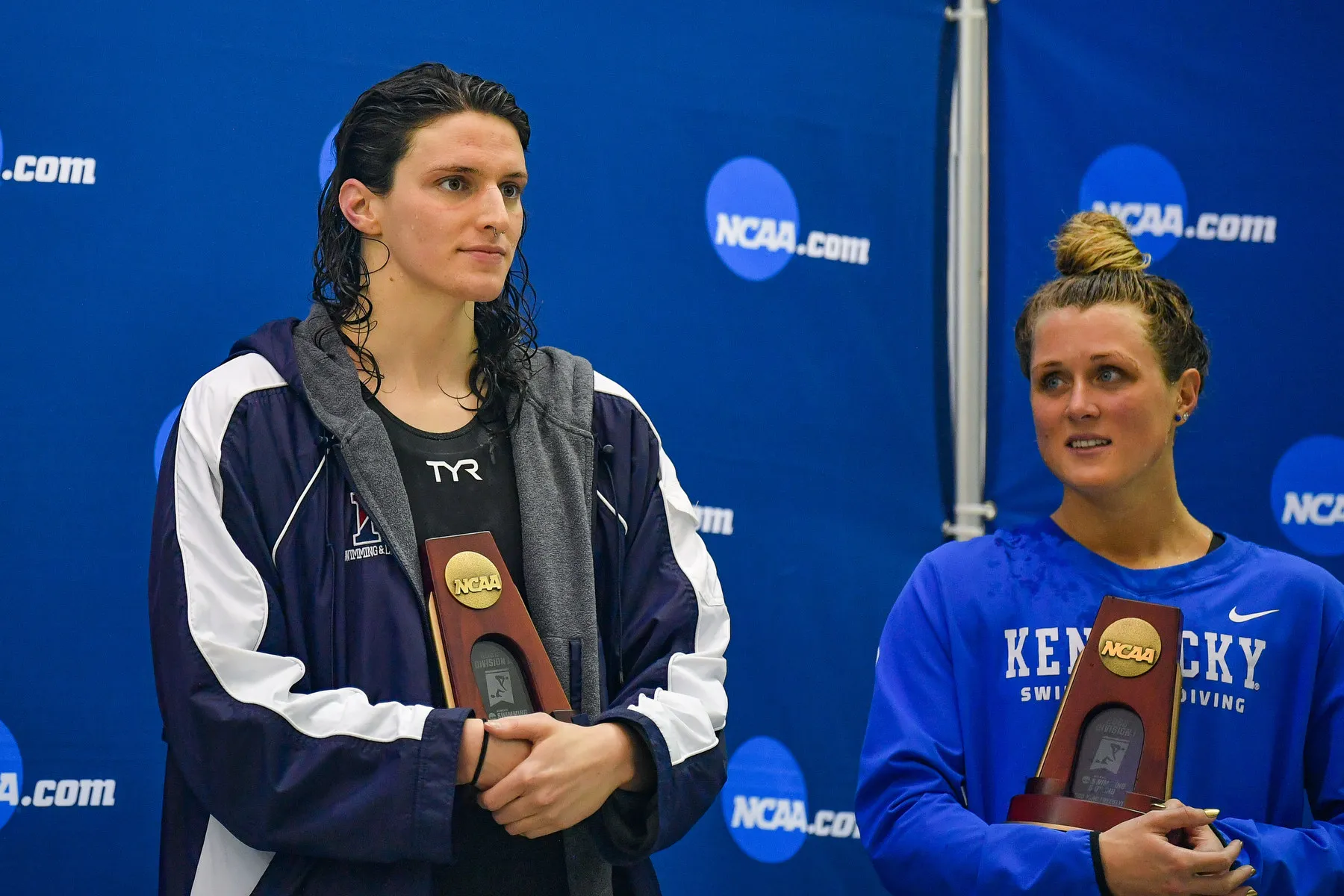 Two women stand side by side holding identical trophies.