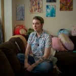 Ellis sits on a sofa surrounded by stuffed animals.