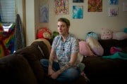 Ellis sits on a sofa surrounded by stuffed animals.