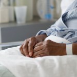 A Black woman's hands are shown as she lays in a hospital bed.