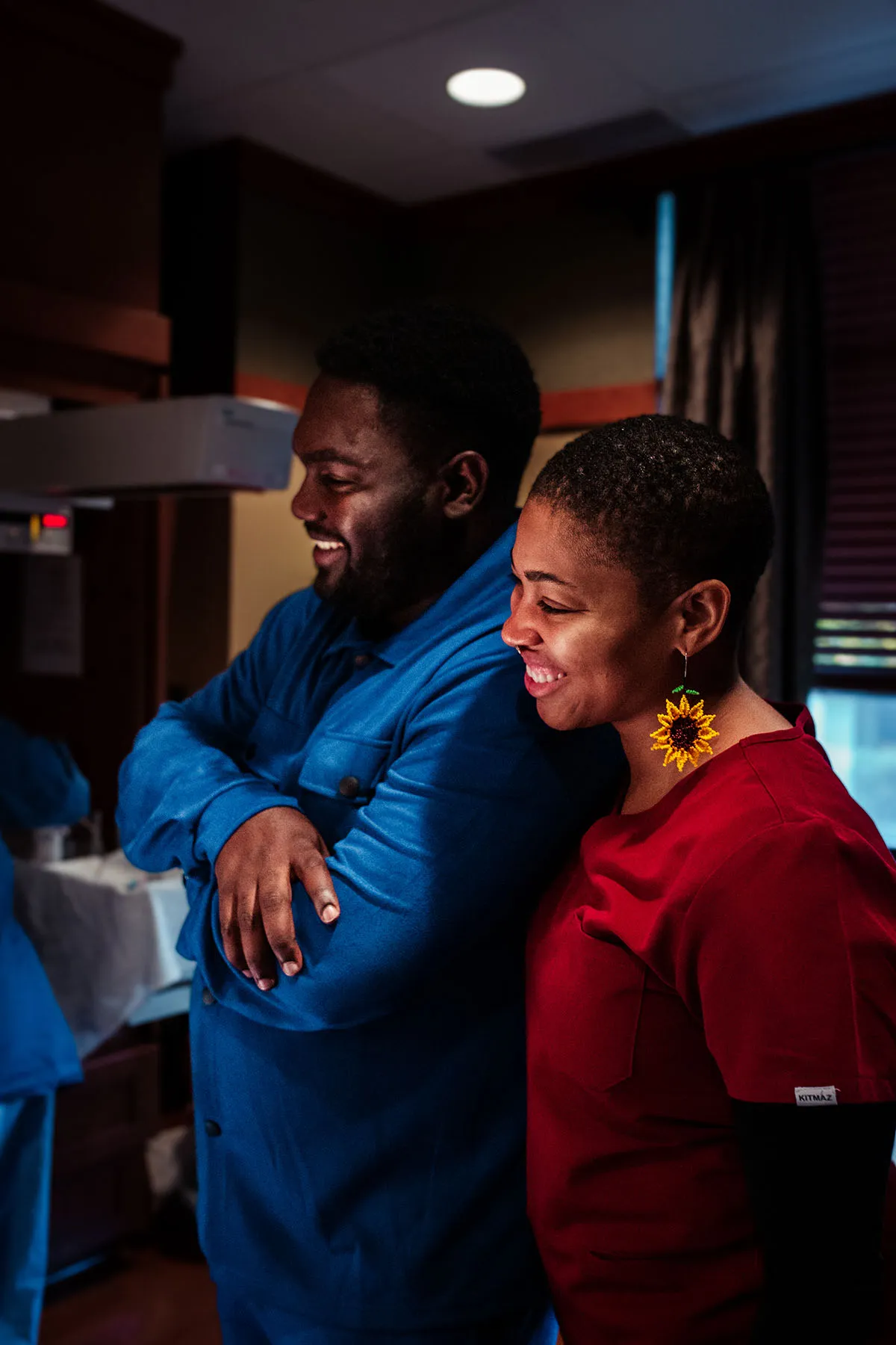 Danielle Lyles Barton, postpartum specialist and doula, stands in the delivery room with the family after the birth of a child.