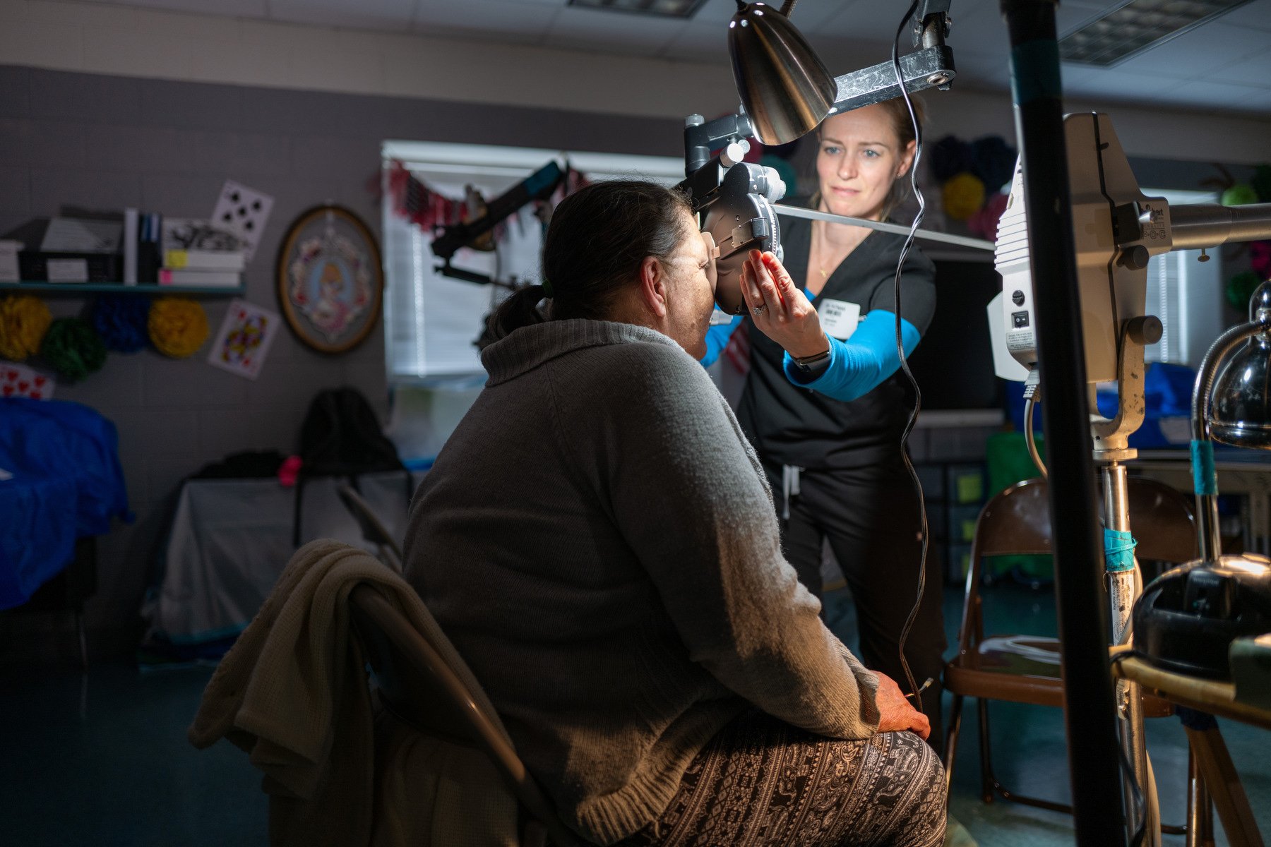 A doctor gives a person an eye exam in a clinic setting.