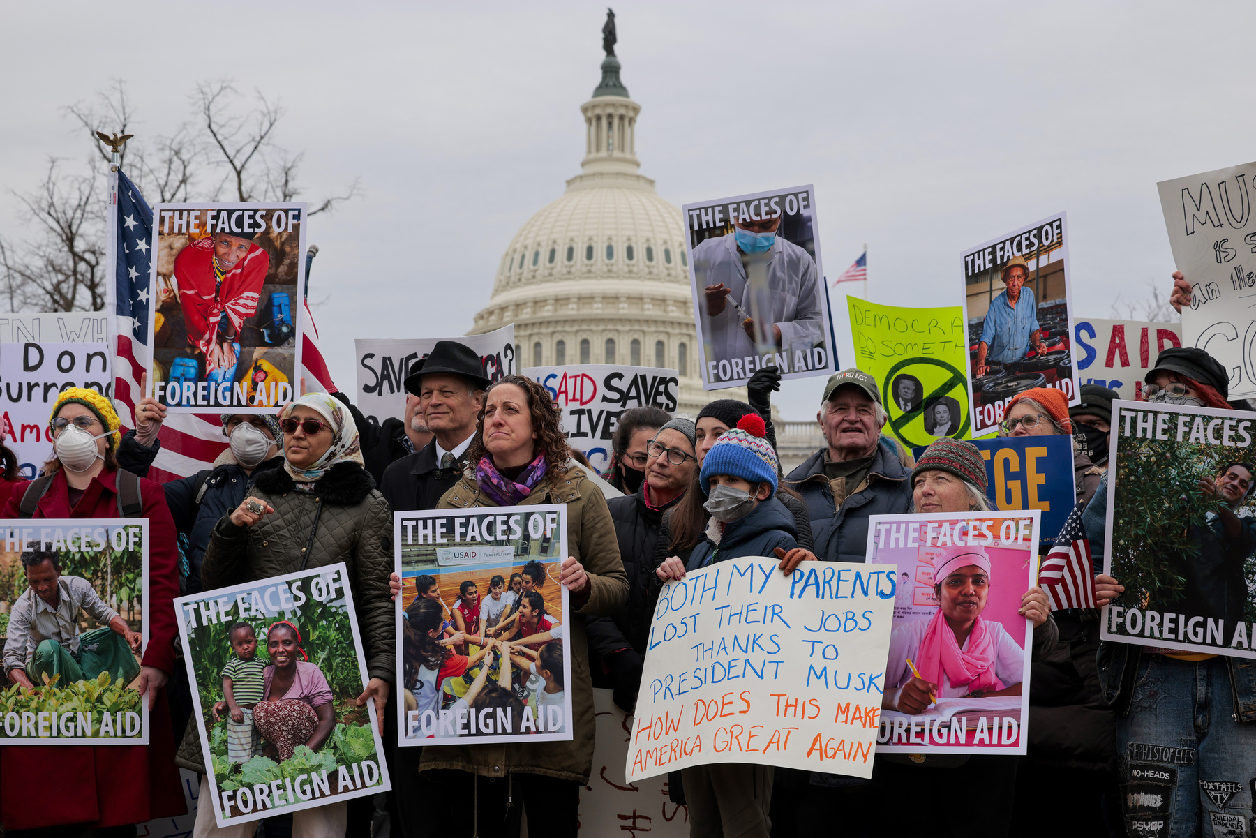 Supporters of USAID rally with colorful signs and posters on the grounds of the U.S. Capitol.